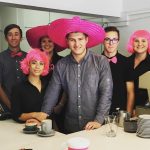 A group of young adults wearing pink wigs and hats