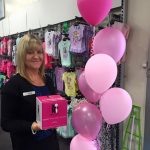 Woman holding up McGrath Foundation Donation box with pink balloons