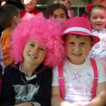 Two kids in a pink wig and hat with overalls