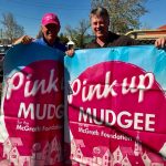 Two men holding up Pink Up Mudgee banners
