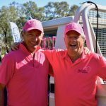 Two men wearing pink shirts and hats